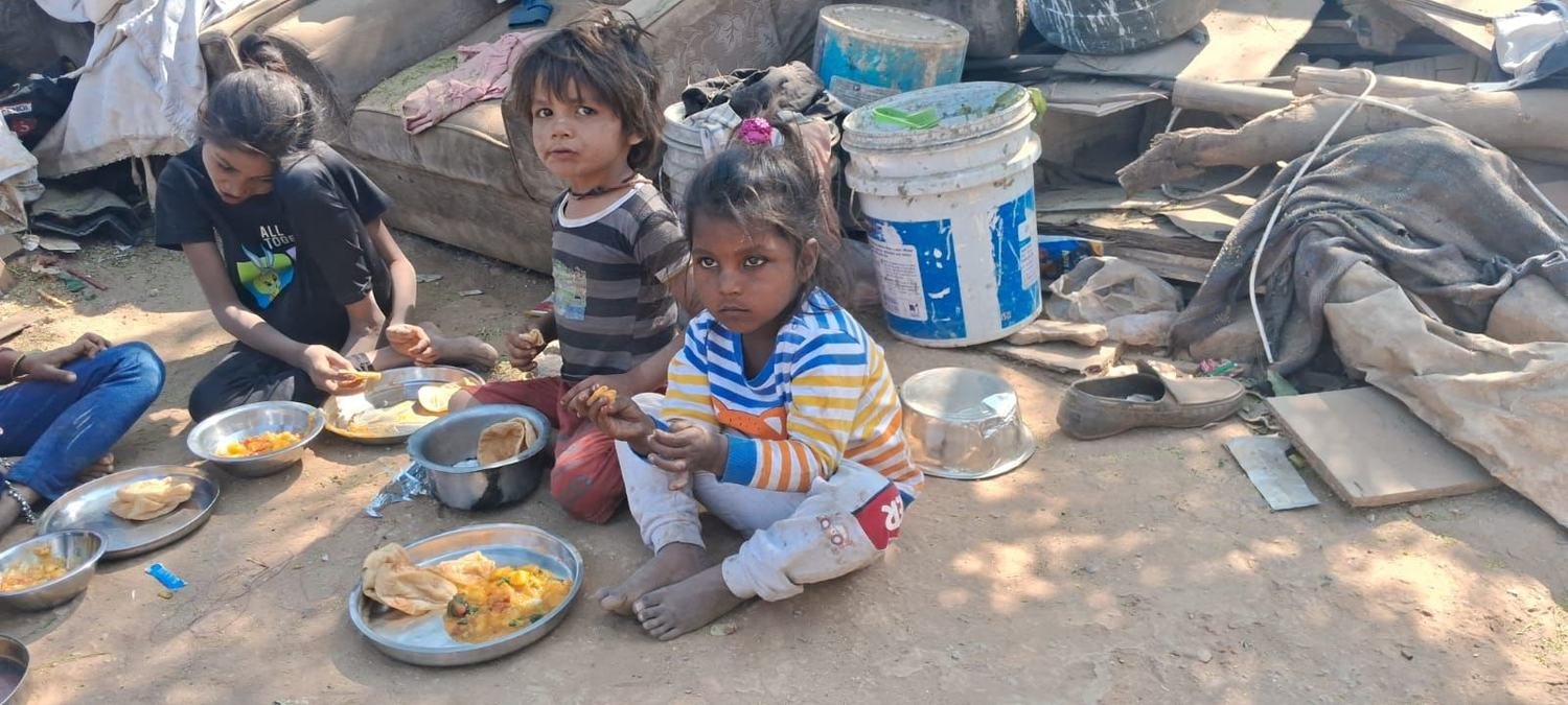 Volunteers serving a hot meal to children on the roadside